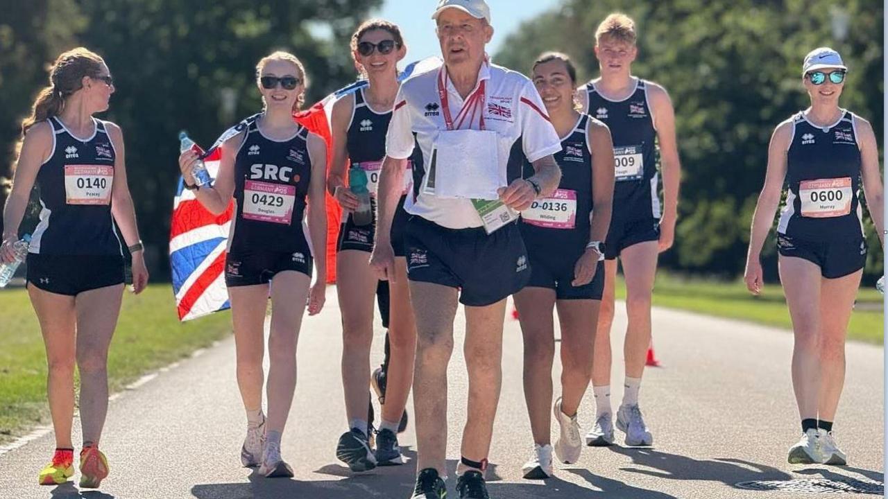 An 89-year-old man who has won four medals at the World Transplant Games, he is running with six younger competitors running behind him holding a union flag.