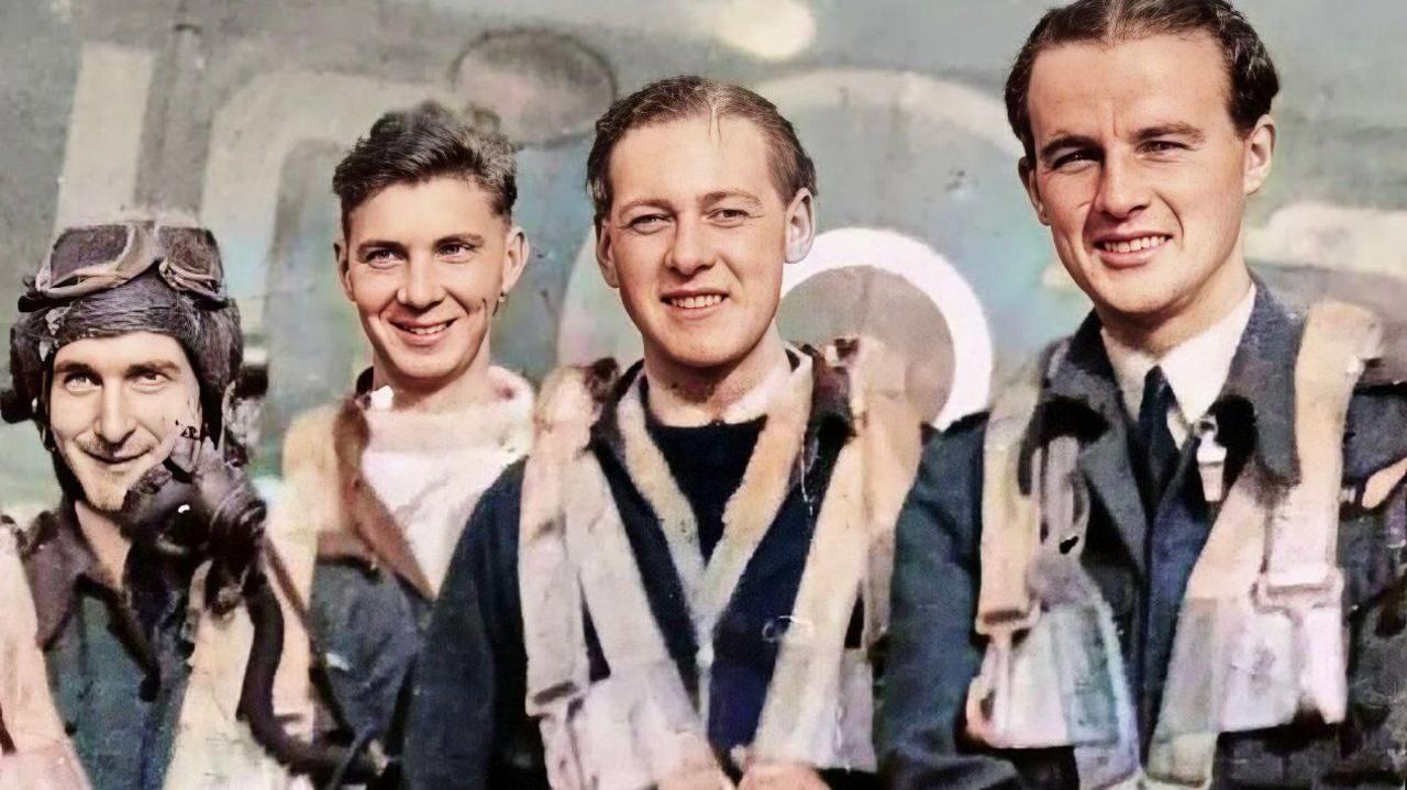 A World War Two phtograph of four airmen, wearing flying kit over their uniforms, posing smiling in front of an aircraft.