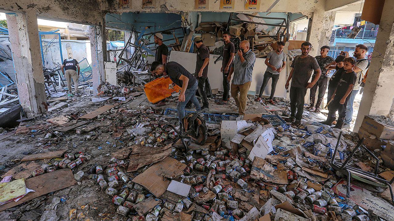 People gather around a burnt out school, with what look like cans of food all over the floor, while searching for survivors after an Israeli strike at the al-Jaouni school in Nuseirat refugee camp, in central Gaza, on 11 September 2024