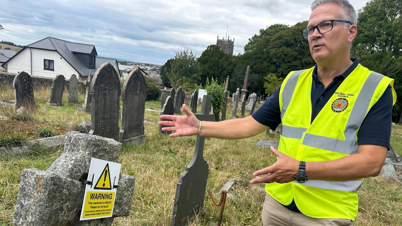 Ian Bovis in a high-viz jacket in the churchyard. Graves behind him.