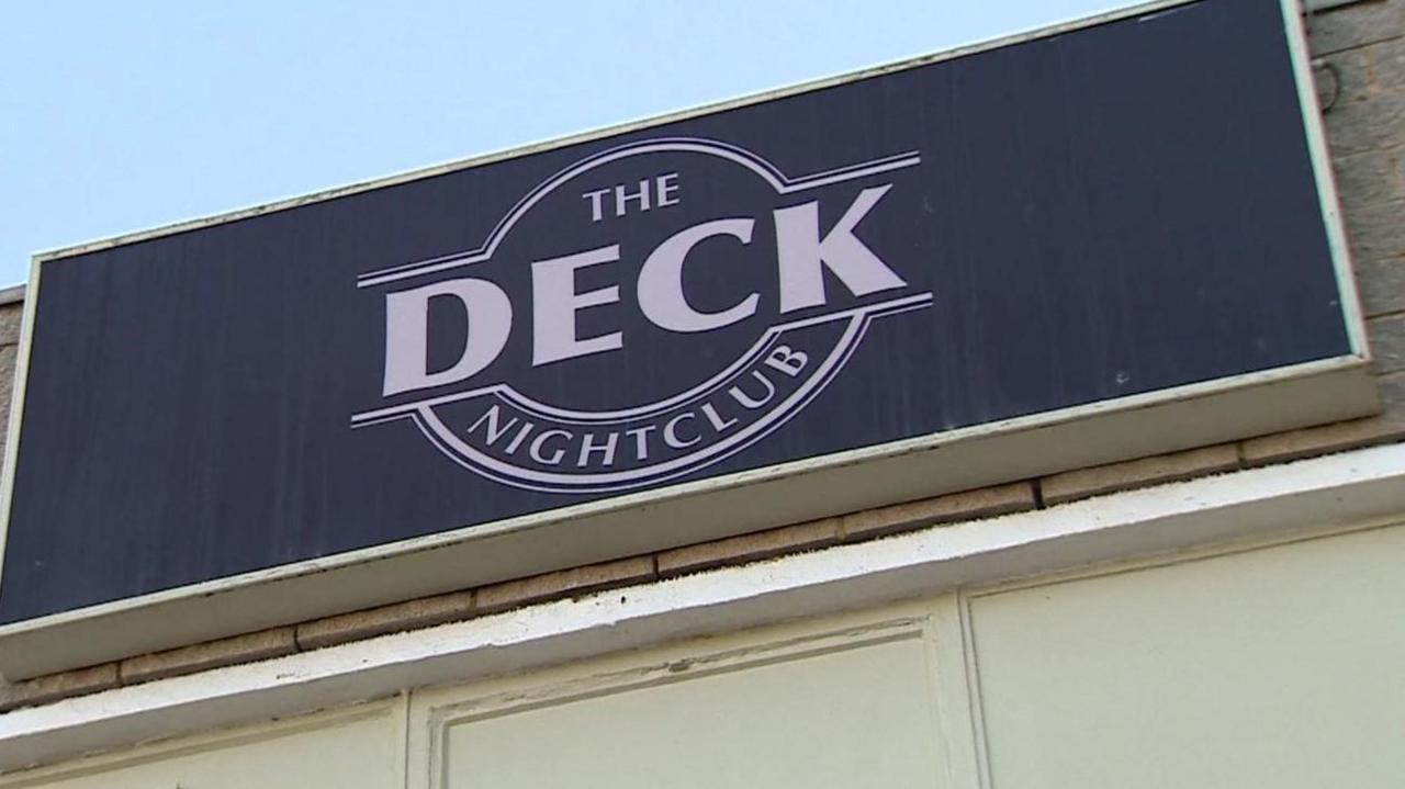 A close up of the club's sign in white letters with a black background.