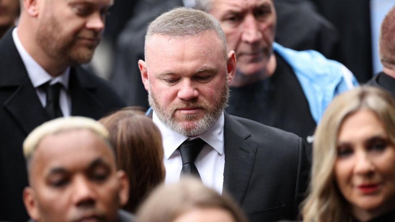 Wayne Rooney has his head bowed as he arrives at the funeral service of the boxer.