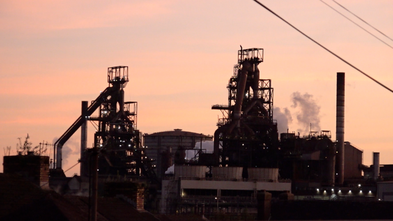 Dau o ffwrneisi chwyth gwaith dur Port Talbot a nifer o adeiladau eraill ar y safle. Mae mwg gwyn yn codi o'r gwaith wrth i'r haul machlud a throi'r awyr yn binc.