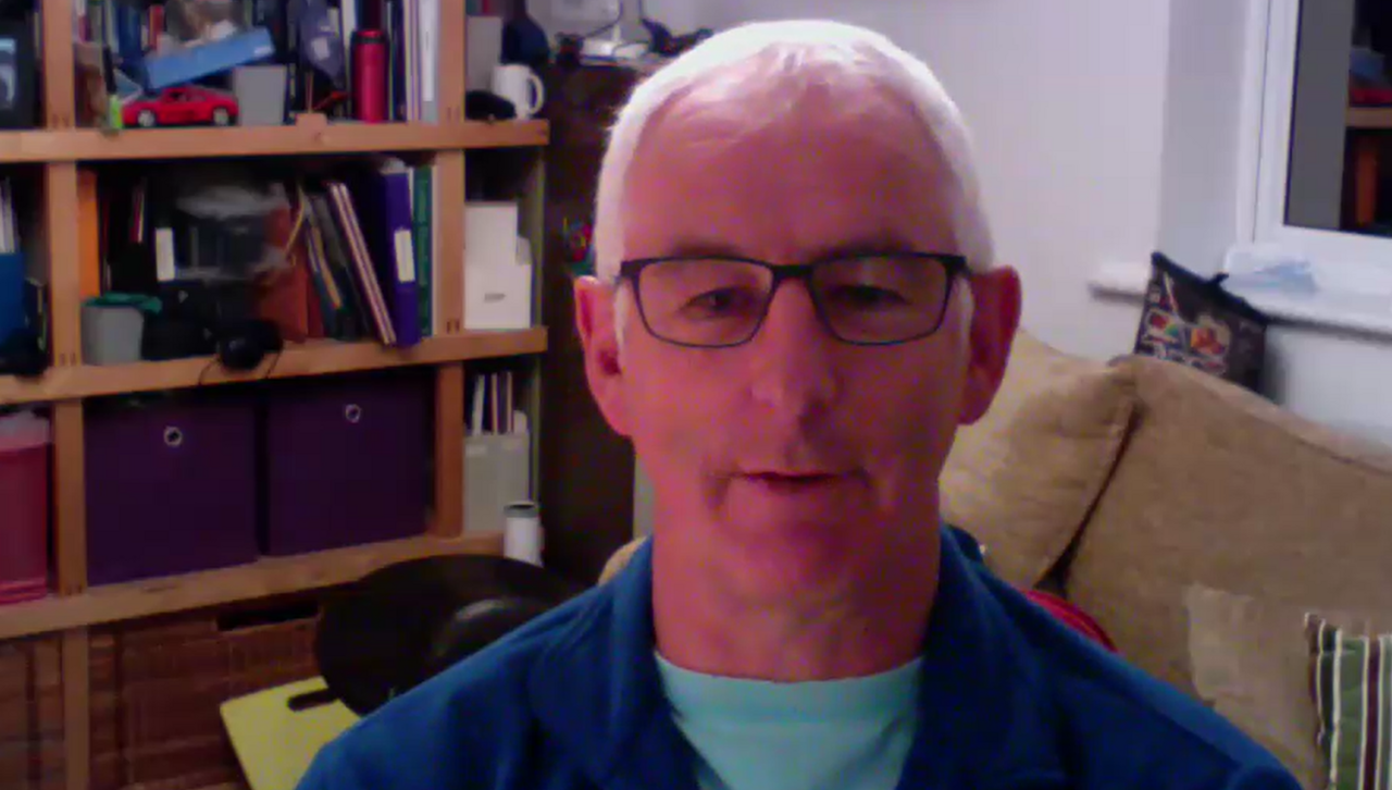 Gary Waller sits in his home office. He has white hair, glasses and wears a blue jumper.