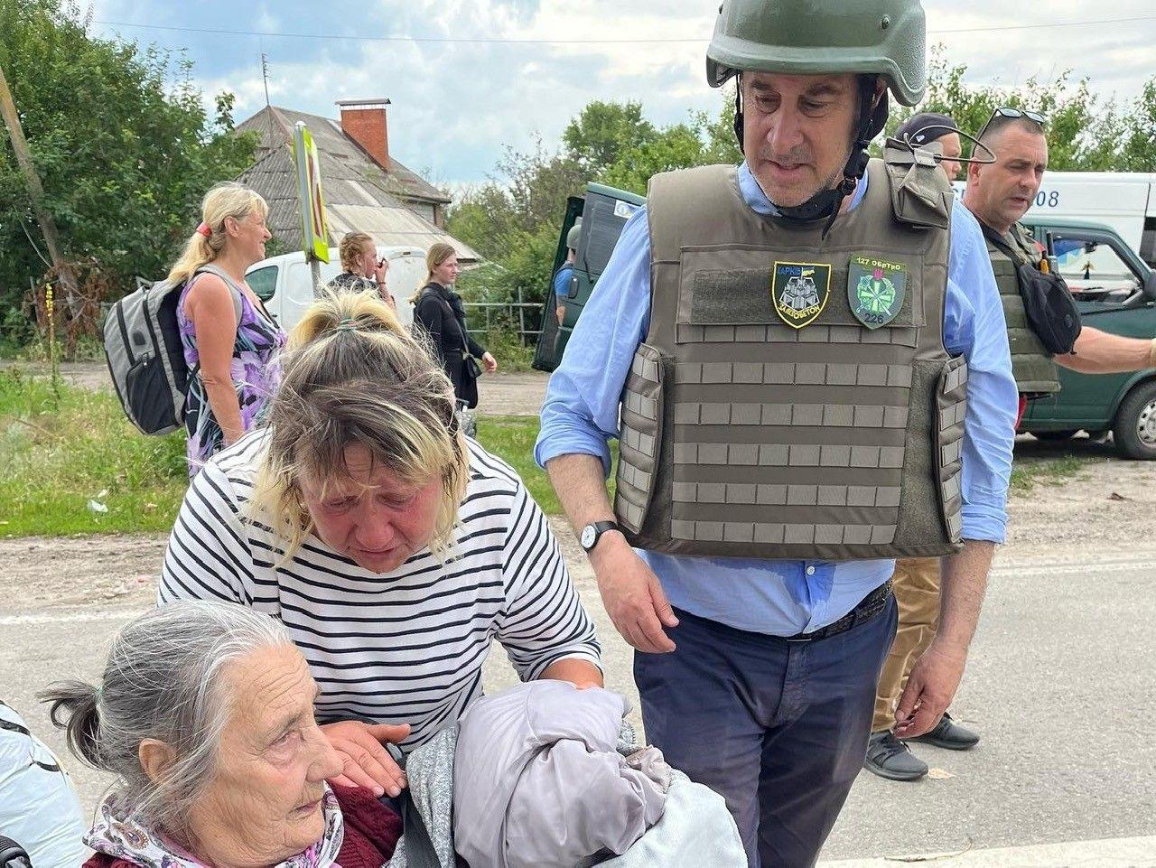 Brooks Newmark wearing protective army clothing with two female Ukrainian refugees.