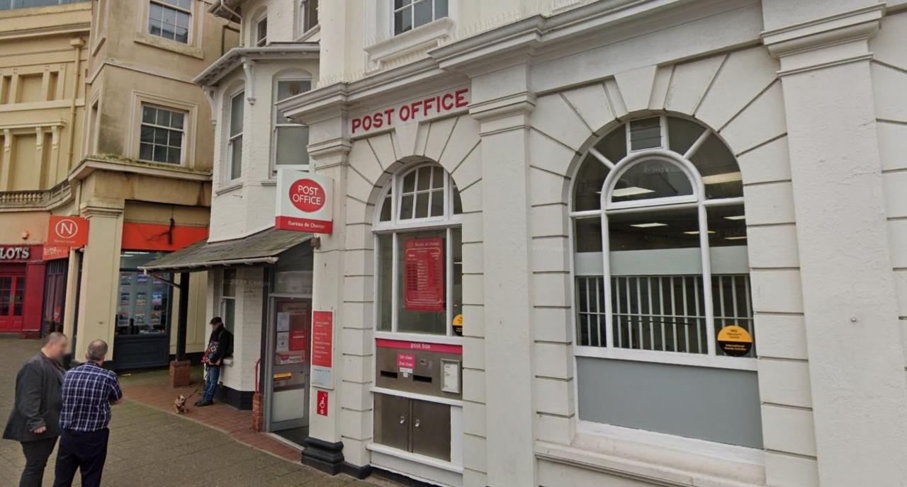 The exterior of the Post Office in Teignmouth with two men standing talking in the bottom left-hand corner of the shot