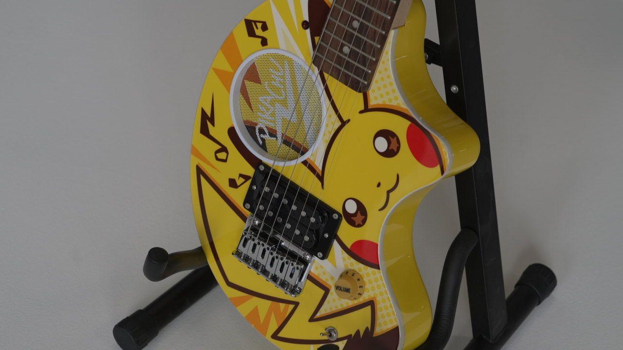 The Fernandes Zo-3 Pokemon-themed limited edition electric guitar. It is yellow with the character Pikachu painted on it. It is sitting on a black stand.