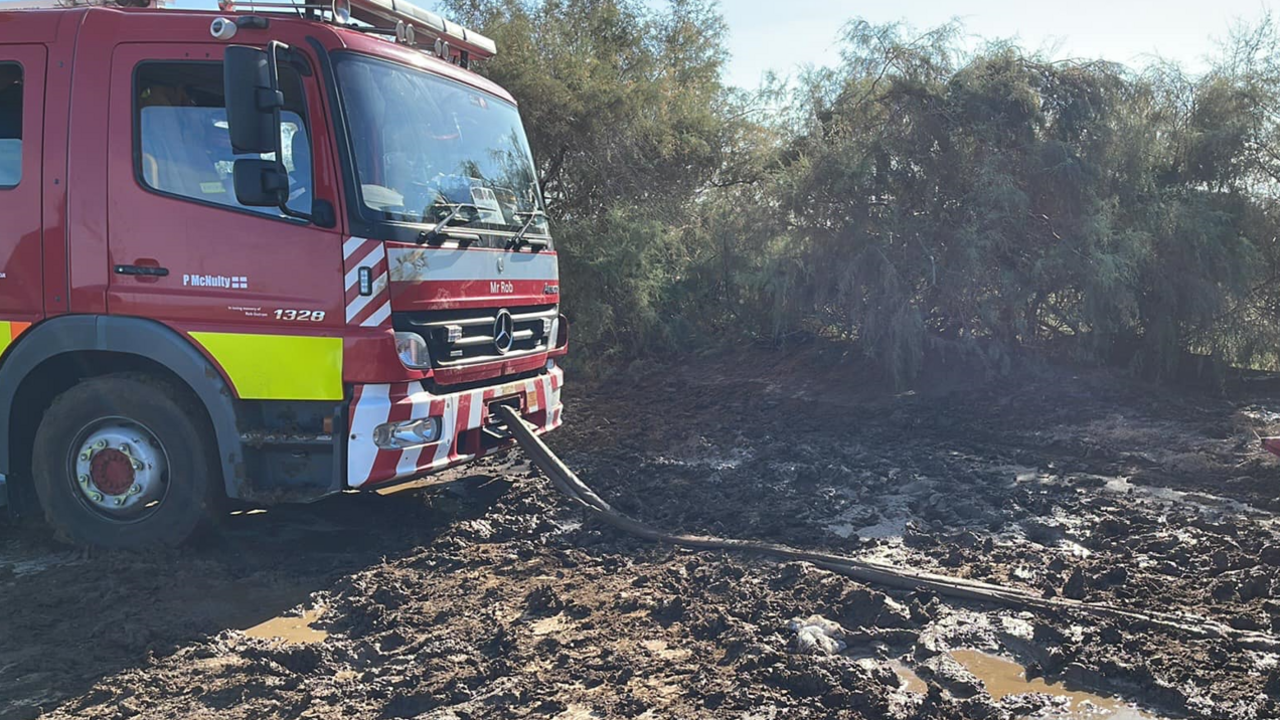 The front of a fire engine with a tow rope attached, stuck in heavy mud