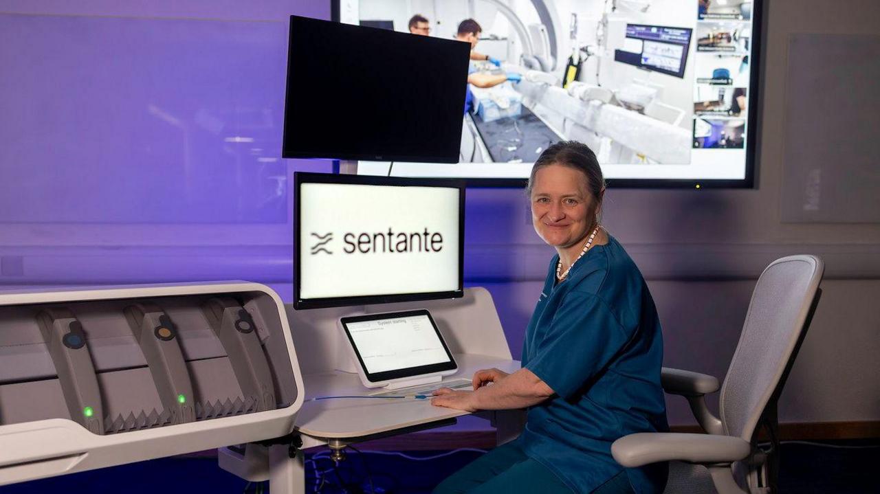 A woman sitting in front of a machine carrying out a remote thrombectomy