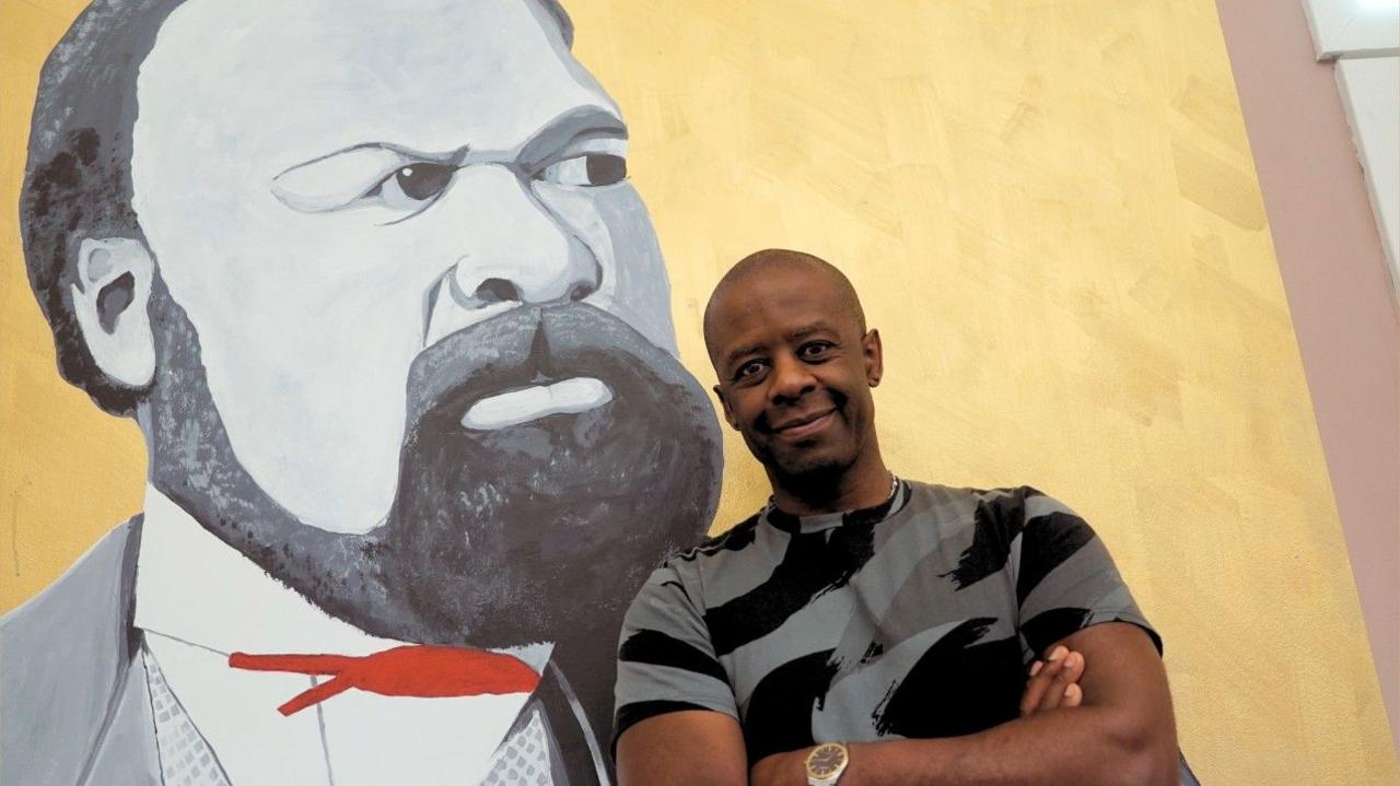 Adrian Lester standing next to a mural at the SCRUM Theatre