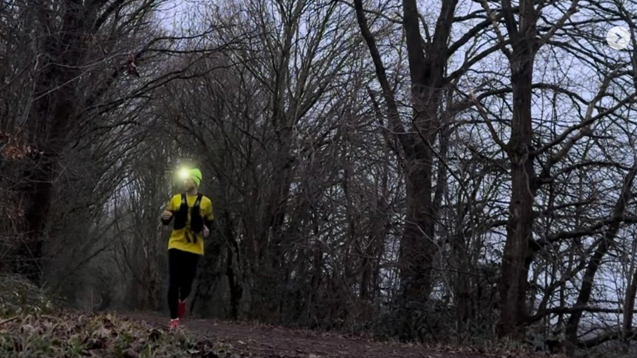 man running through woodlands in darkness, with a head torch on 