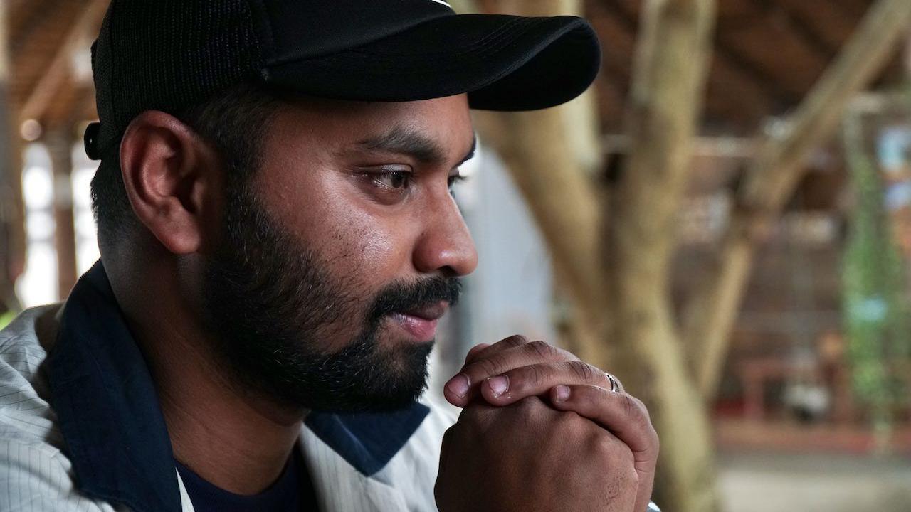 Ariyan wearing a black cap and a collared t-shirt.