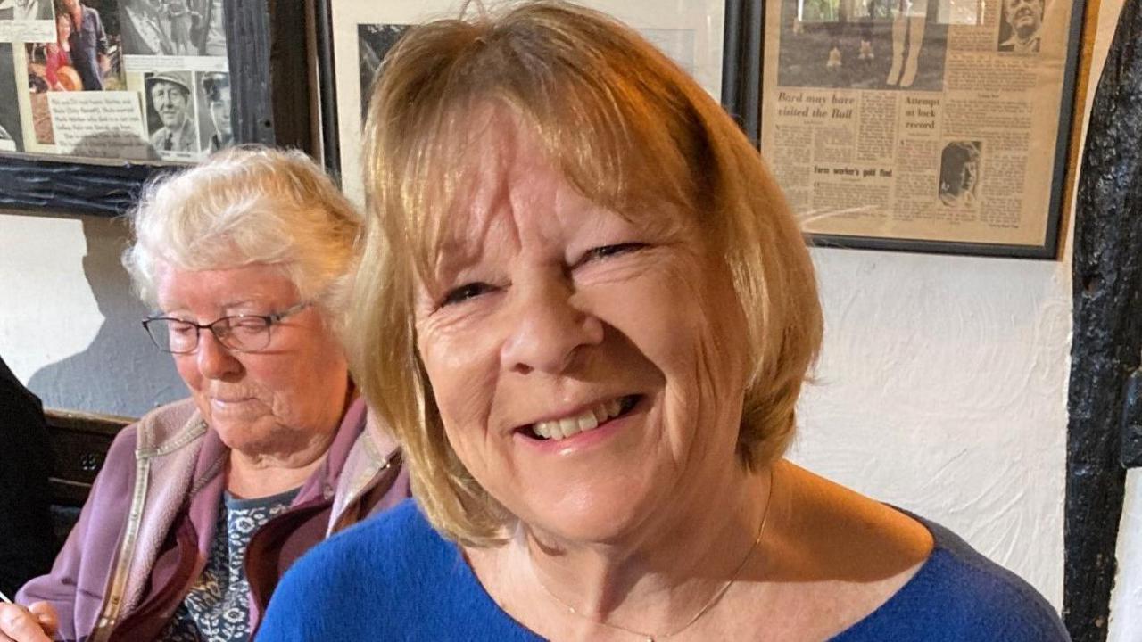 Melanie Hart wearing blue and smiling at the camera in a pub