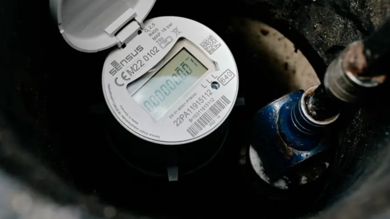 We can see part of a smart meter. A white circle with numbers, branding and a barcode on it. In the middle, there's a digital display.