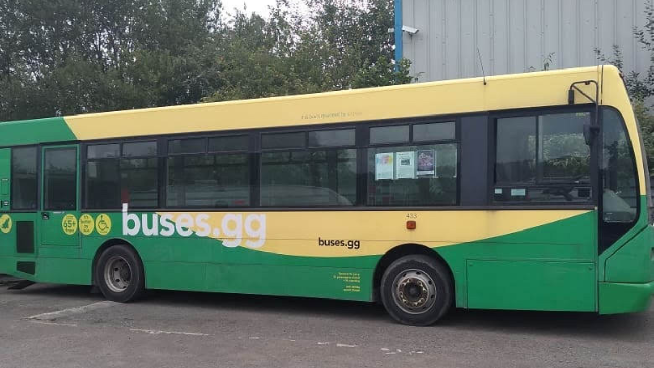 A green and yellow bus with the web address buses.gg on the side.