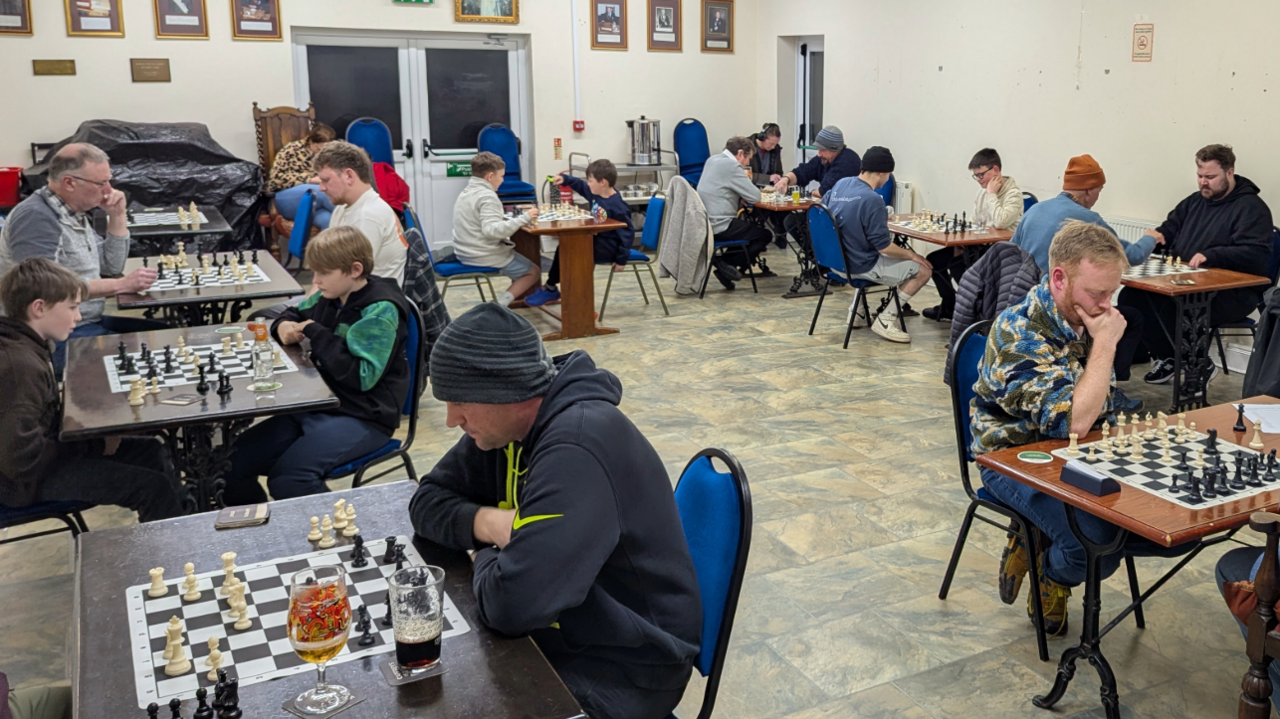 Llun yn dangos ystafell llawn pobl yn chwarae gwyddbwyll.