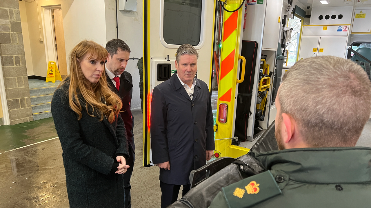 Sir Keir Starmer and Angela Rayner talking to a man at the rear of an ambulance that has its doors open. They are outside the Princess Alexandra Hospital