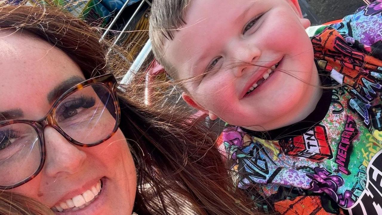 Sharleen Wray has long brown hair and glasses. Her son, Billy, is in a multi-coloured top and has short brown hair.