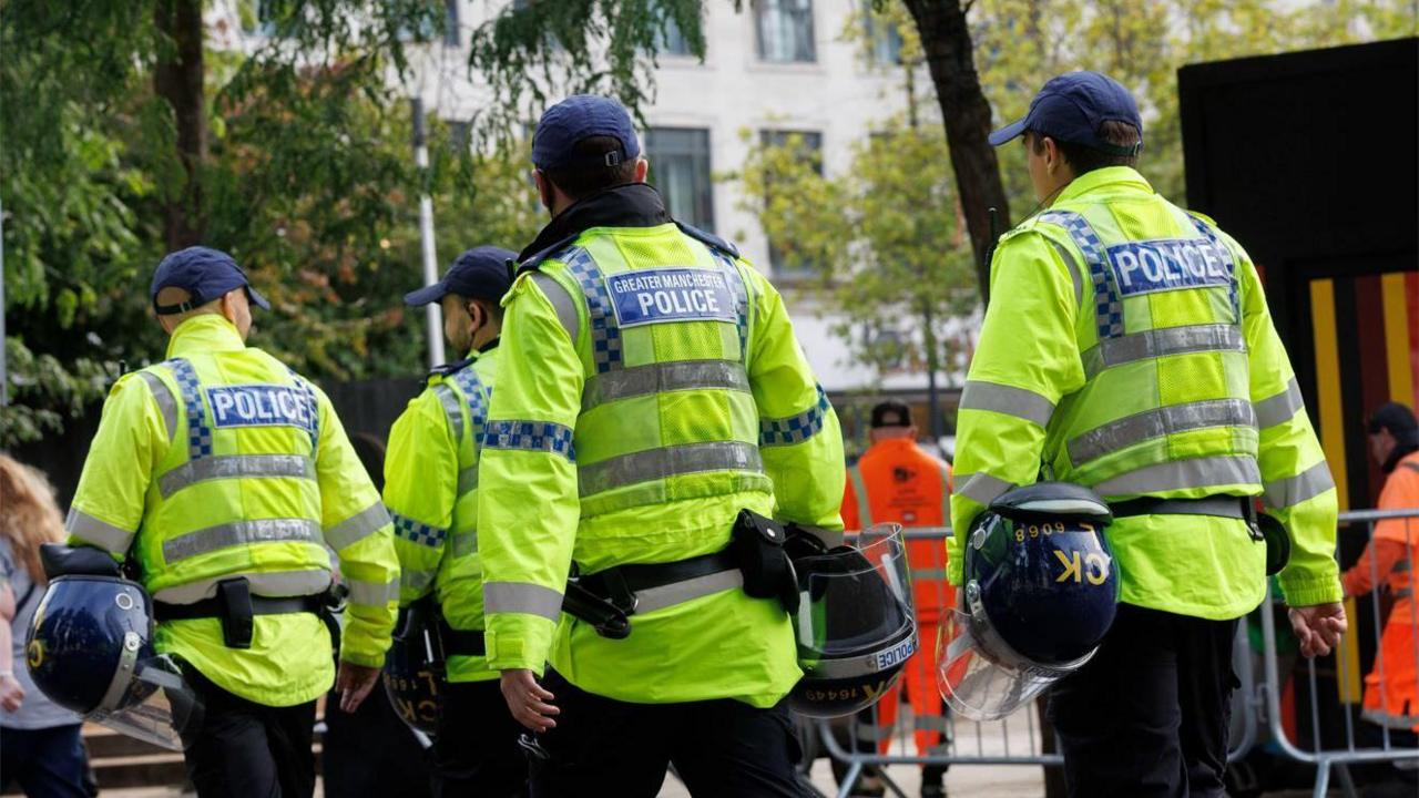 Greater Manchester Police officers line up with riot gear at a protest in Manchester