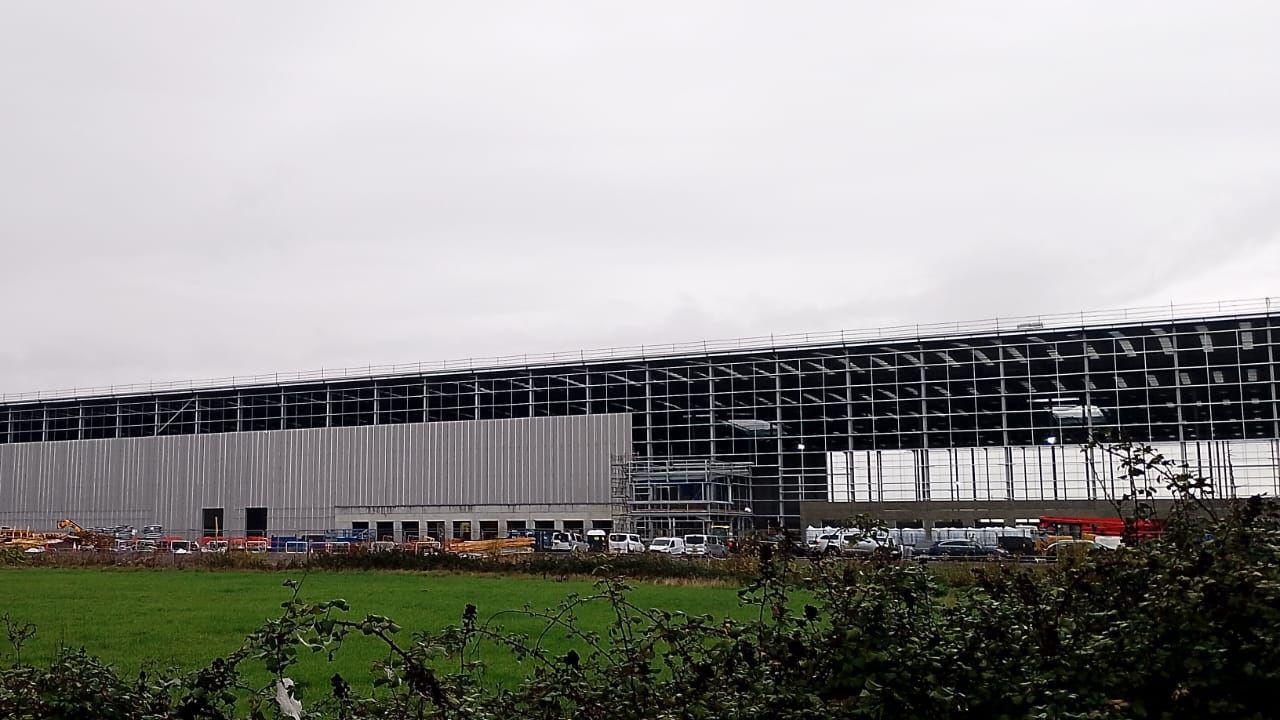 The image shows a giant warehouse being built on land next to the Severn Estuary but close to houses in Pilning.