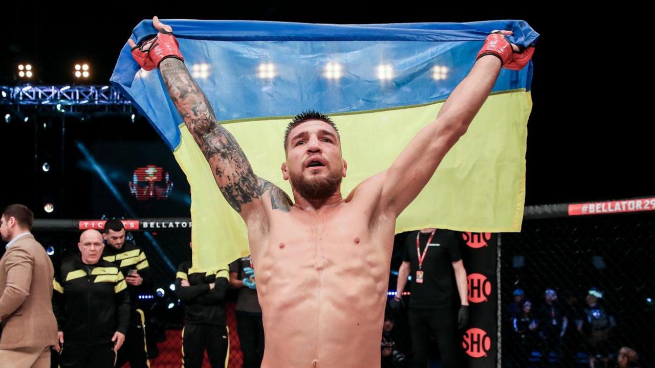 Yaroslav Amosov raises a Ukrainian flag after beating Logan Storley in February 2023