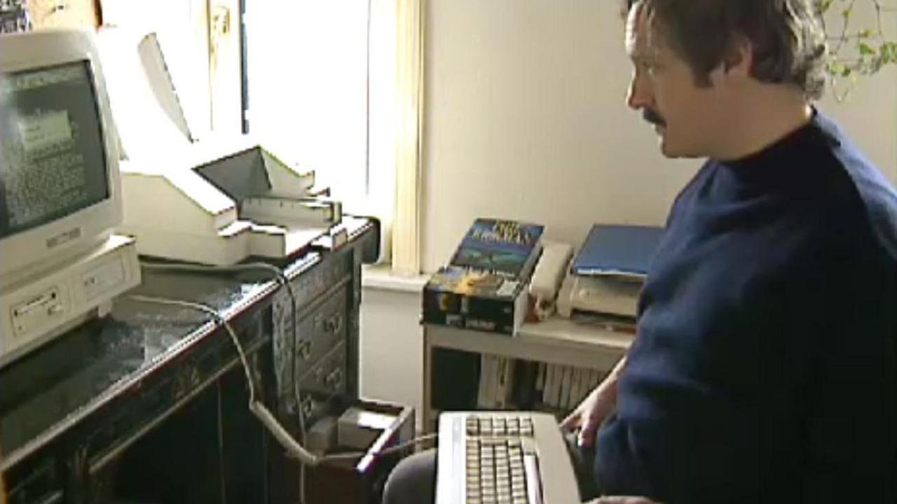 Supernatural author Phil Rickman sits on the right working at his desk in 1994 using a computer typical of the period