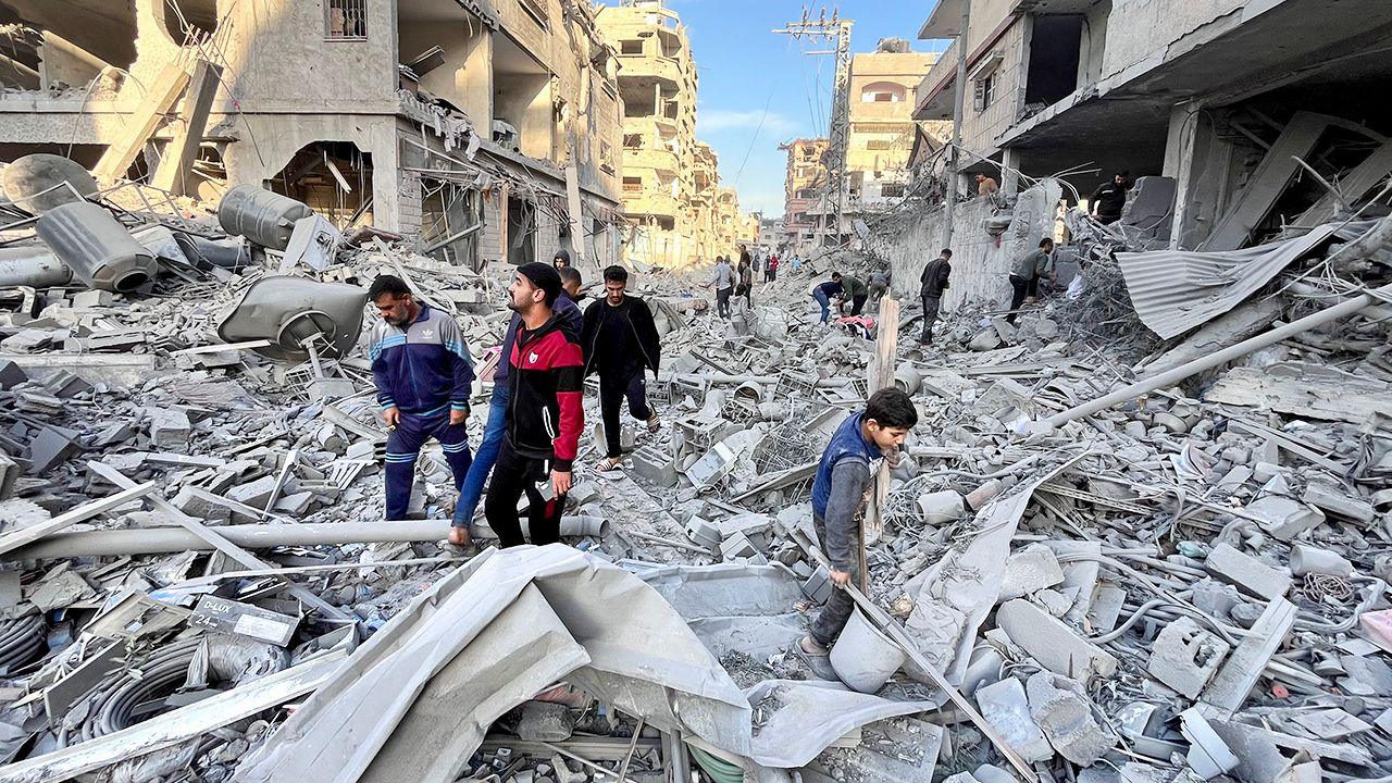 Palestinians search for survivors among a mess of rubble in a street after an Israeli air strike in Beit Lahia, northern Gaza (17 November 2024)