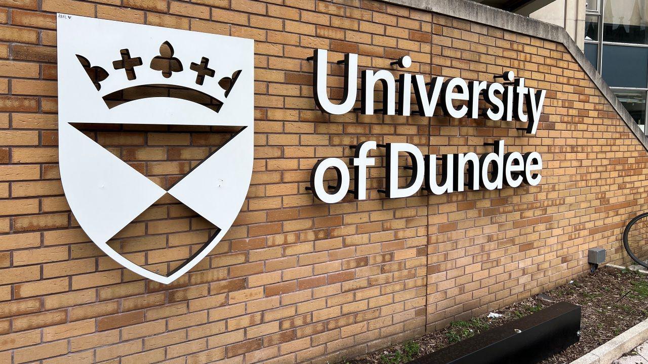 A sign saying University of Dundee affixed to a brick wall