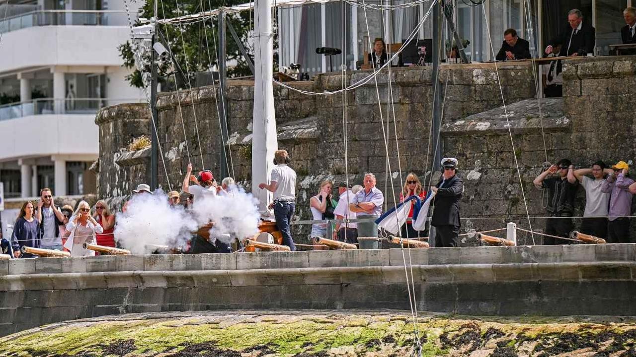 Cannons firing as people cover their ears during the parade at Cowes Week