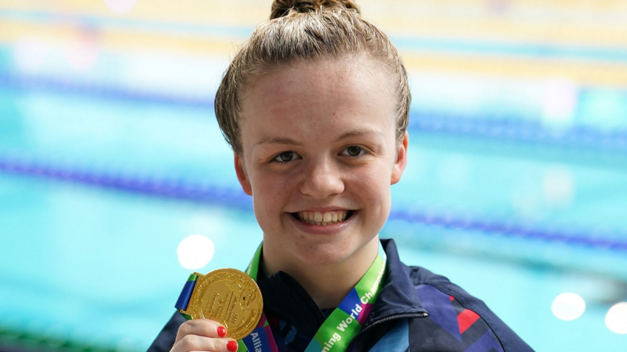 Maisie Summers-Newton holds up a gold medal she won in Tokyo