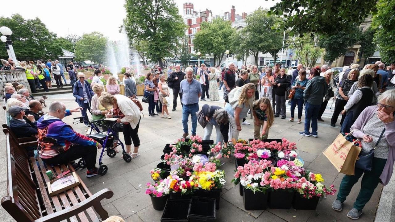 People view floral tributes on a piazza in central Southport