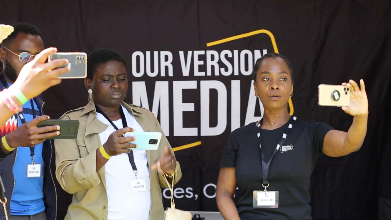 A small group of people holding and looking at smartphones in their hands. The words Our Version Media are visible on a black backdrop behind them.