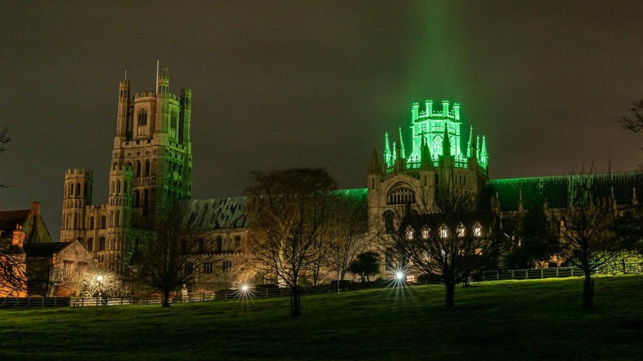 Stone-built cathedral with tower lit up in green light