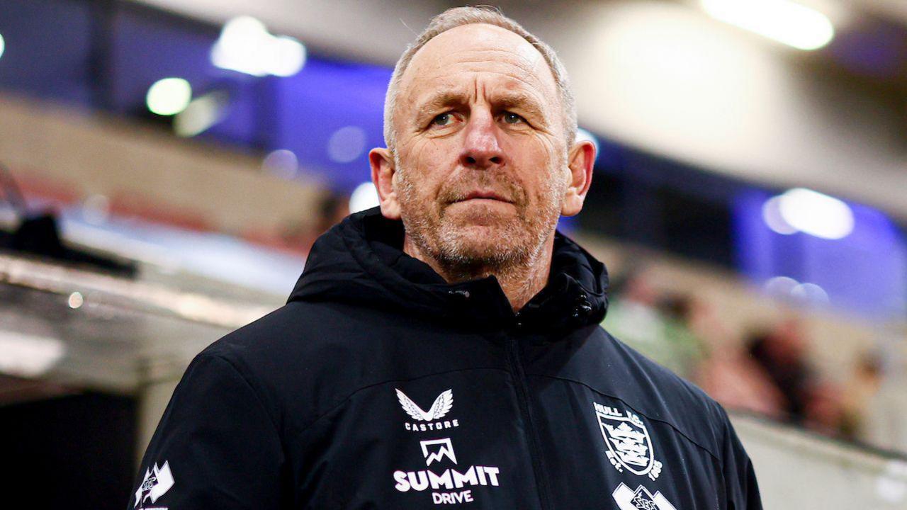 Hull FC head coach John Cartwright watches on from the sidelines in a club-issued black coat