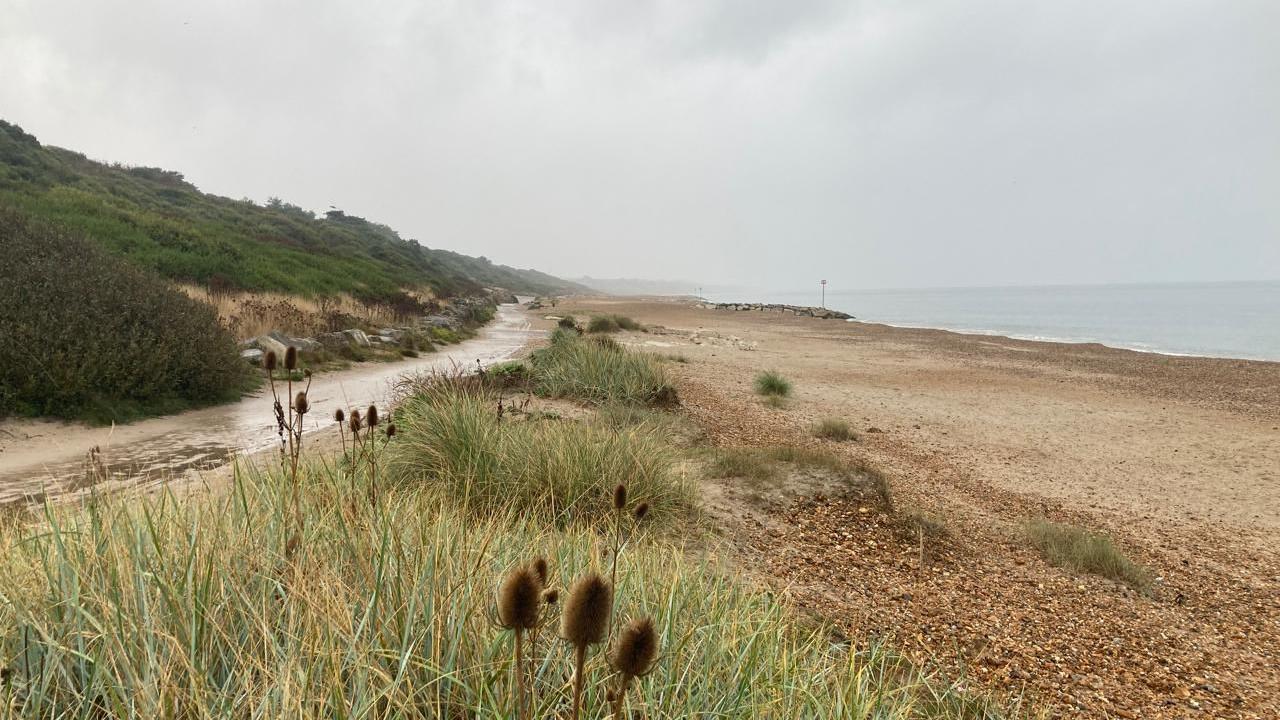 Dark grey clouds loom over the sea and an empty beach in Highcliffe. 