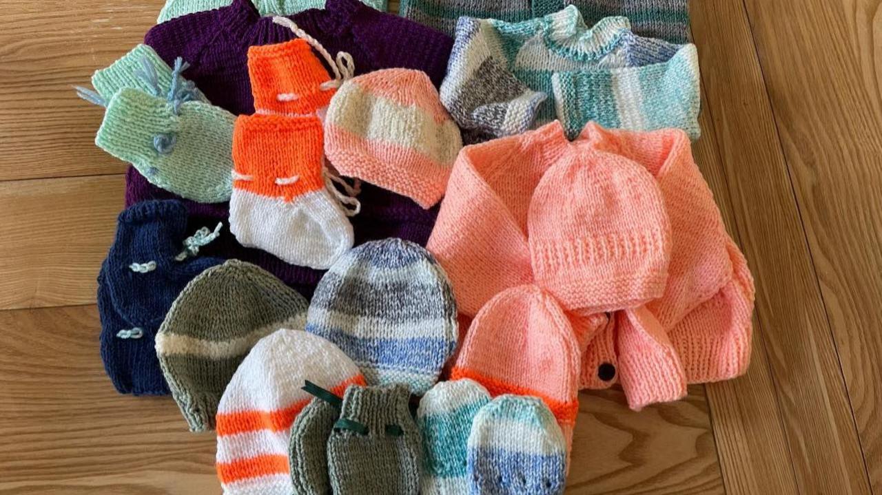 Various multicoloured knitted baby items.