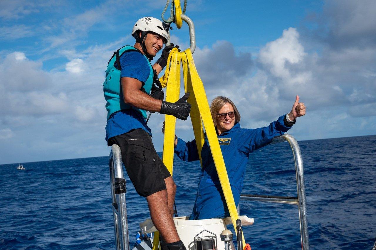 Kathy gives a thumbs up while on a ladder toward ocean