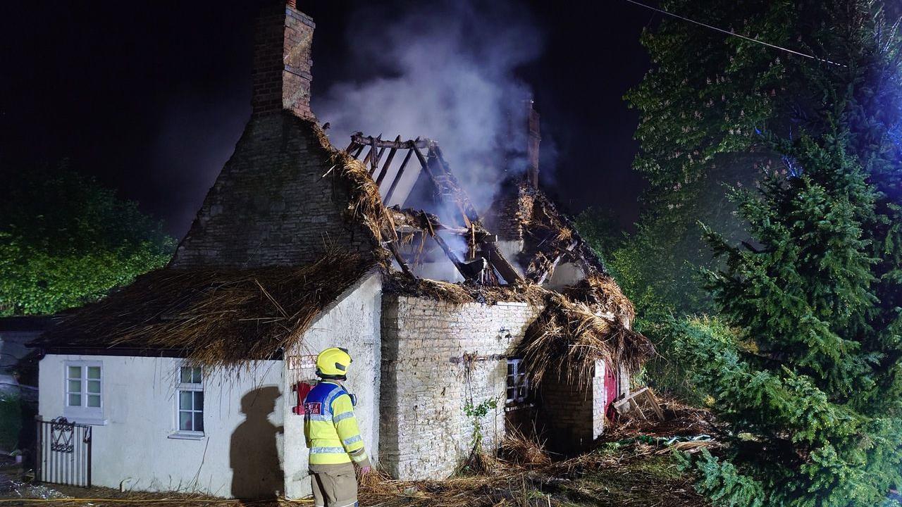A building with a roof that is missing, with smoke emanating from the structure.