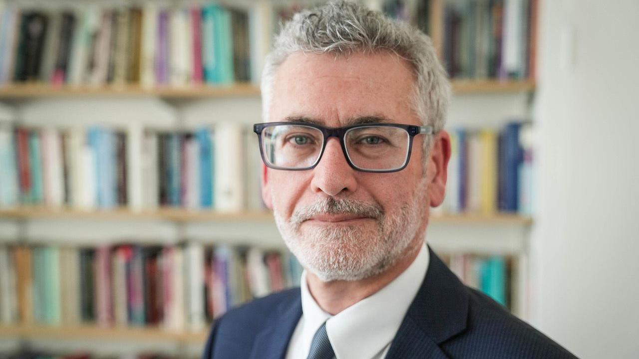 A man with grey hair and glasses wearing a suit