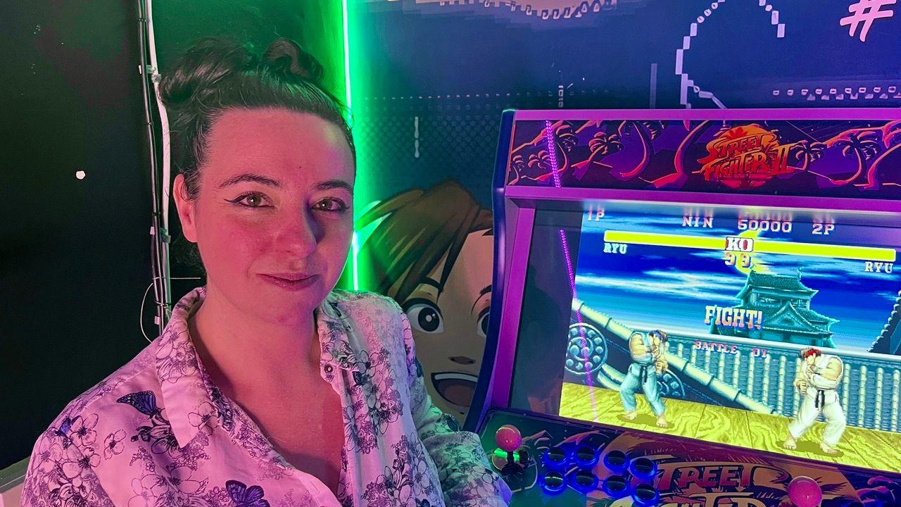 Sapphire Sharkey wearing a patterned shirt in the Hadoken Free Play arcade next to the Street Fighter II game