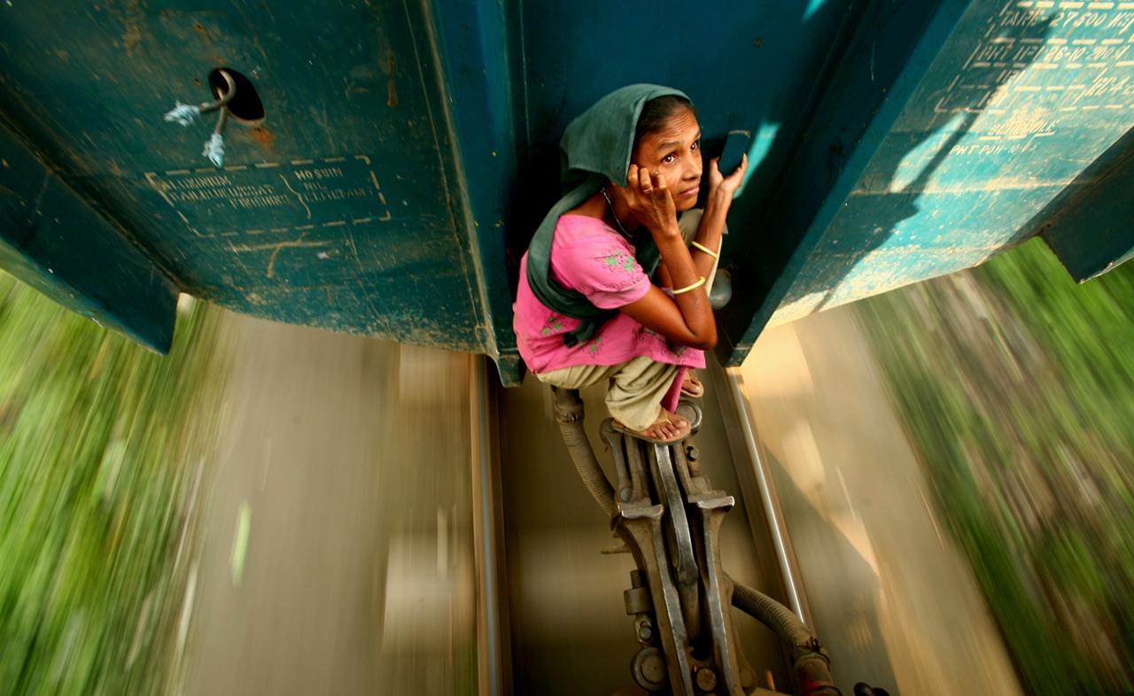 A woman travelling on the locking system of a carriage. Dhaka, Bangladesh