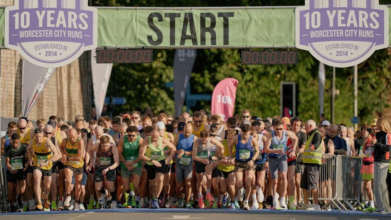 Dozens of runners are pictured at the start line in the bottom half of the image. Near the top is the word start in the centre, while on the left and right are banners saying 10 years Worcester City Runs established in 2014.