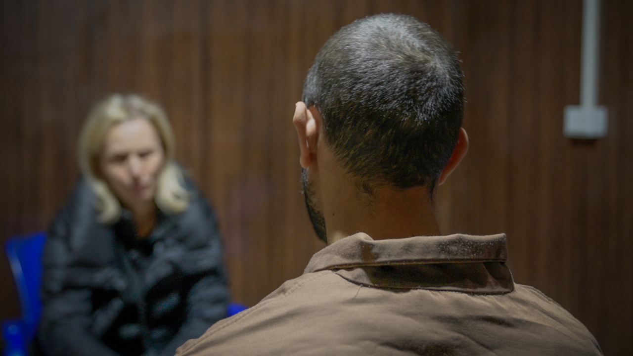 Al Sina IS inmate sits with his back to the camera, facing reporter Orla Guerin who is out of focus