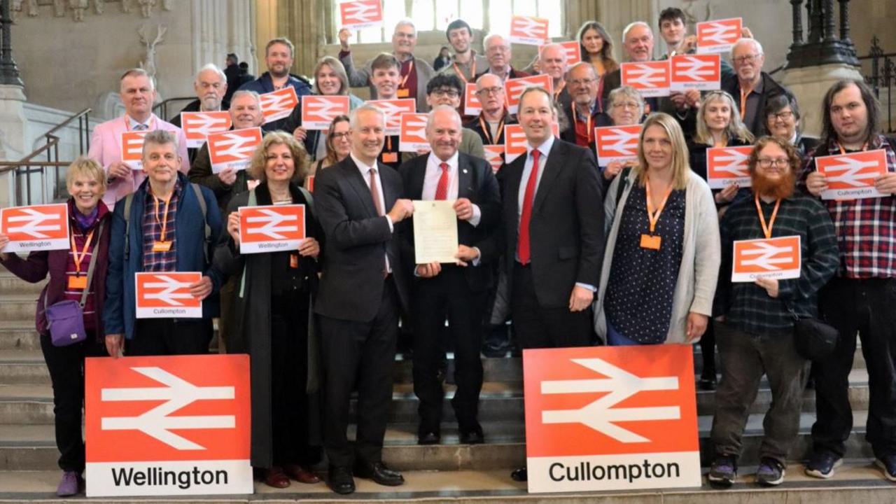 Campaigners for new railway stations in Wellington and Cullompton in Westminster including Gideon Amos MP (left) and Richard Foord MP (right) presenting a letter to Lord Hendy (centre)