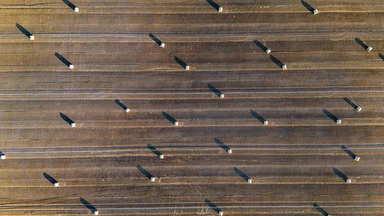 A drone image of a field with bales of straw dotted across the frame