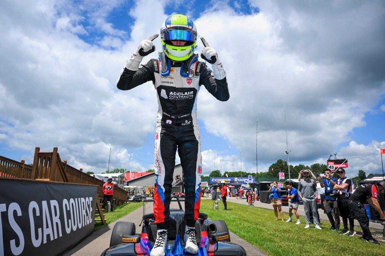 Liam McNeill stands on top of his racing car to celebrate a successful race