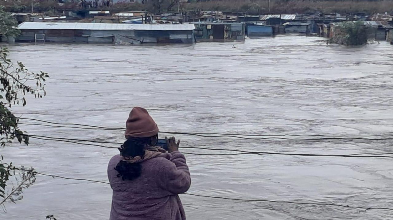 A woman takes pictures in front of a flooded body of water in South Africa's Eastern Cape province