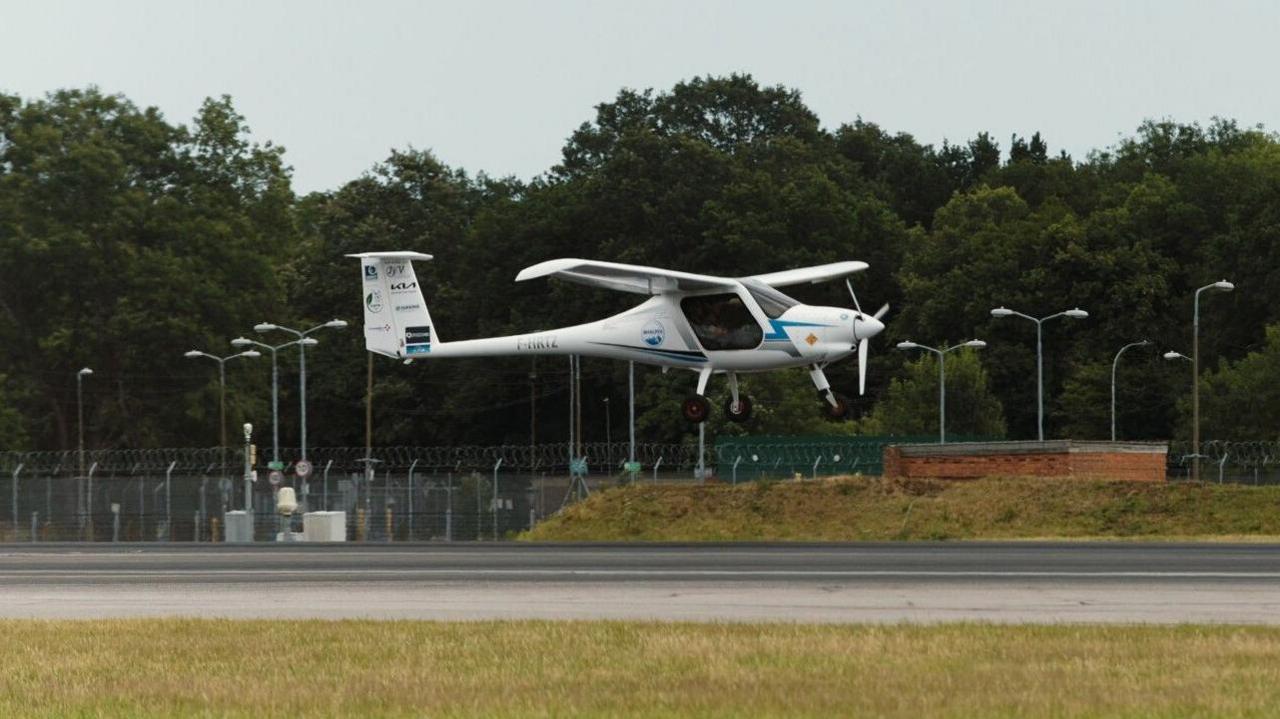 A small which plane coming into land just a few metres above a runway. The image is taken looking at the front right of the plane from the ground