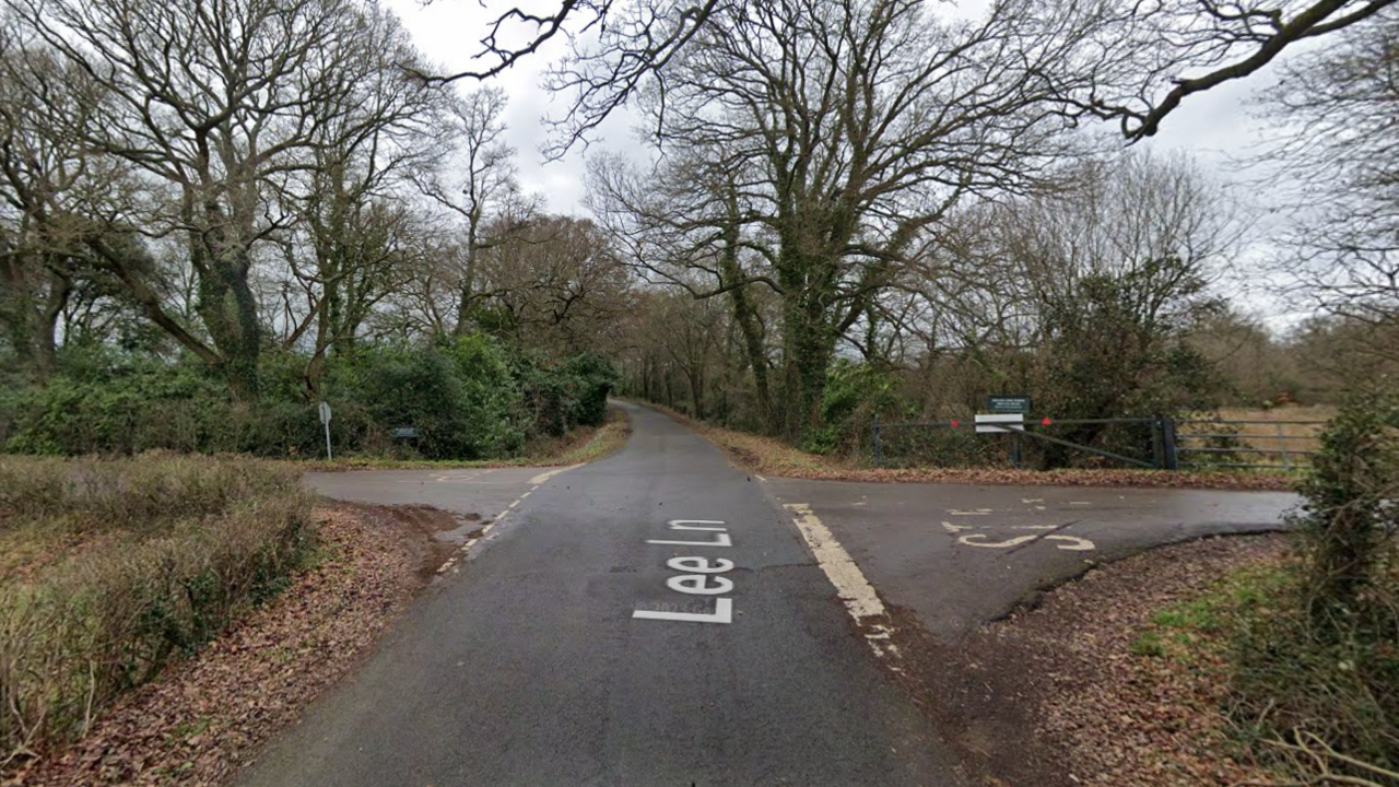 A Google street view screenshot of a crossroads of two country lanes with trees on either side.