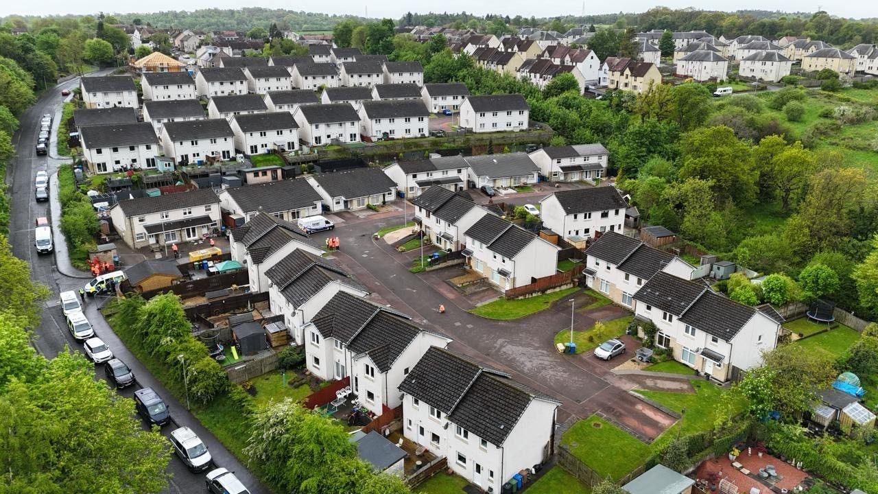 An aerial view of a residential street of white houses